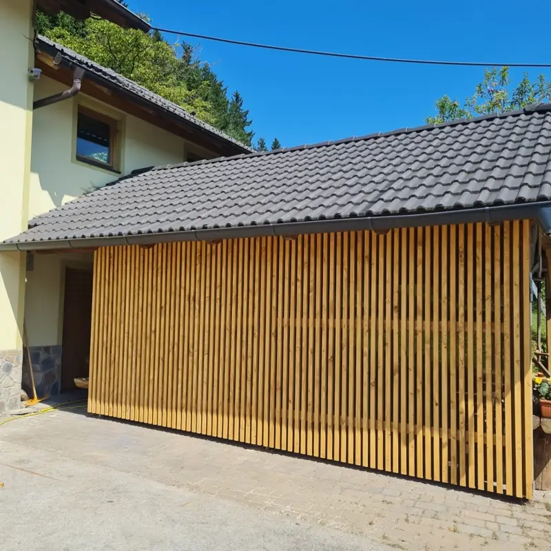 Nadstrešek za avto z lamelno leseno oblogo in temno opečno kritino